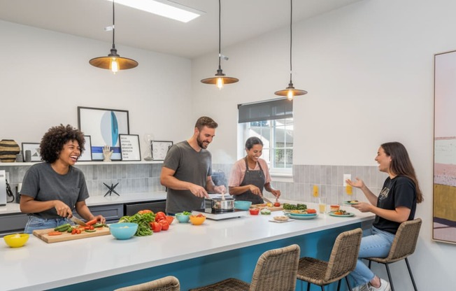 Four people are cooking and eating in a modern kitchen.