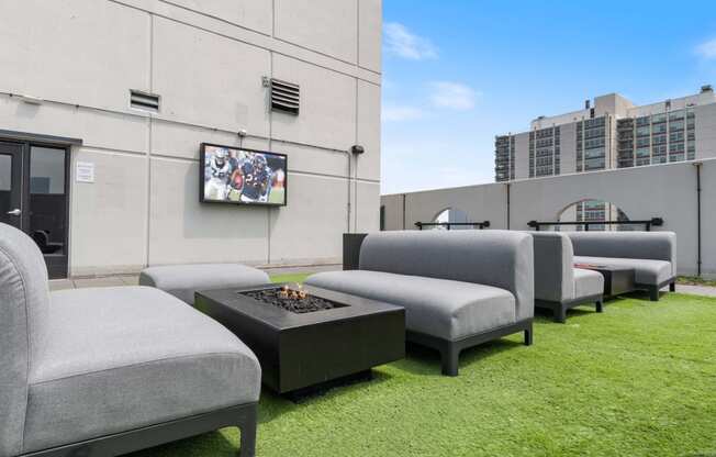 a lounge area with chairs and a fire pit on the roof of a building