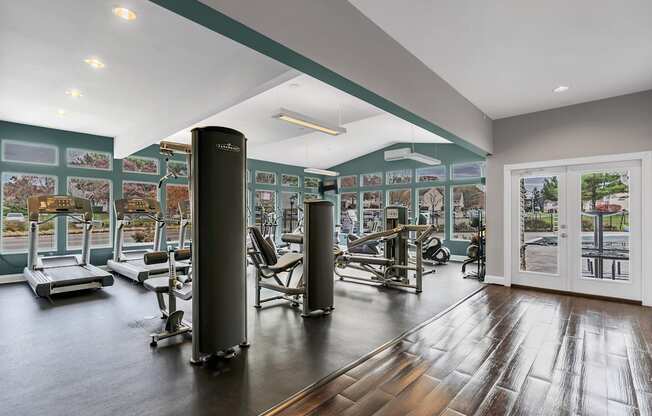 a gym with exercise equipment and a glass door with a view of a parking lot at Misty Ridge Apartments, Woodbridge, VA