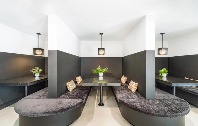 Semi-private dining booths with curved banquette seating, pendant lighting, and intimate table settings suited for casual meals, work sessions, or conversation.