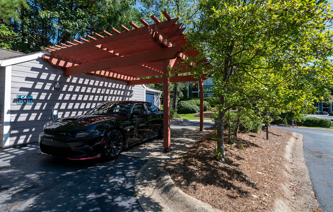 a car parked in a Car Wash amenity at Wynnwood Vinings apartments under a wooden shade