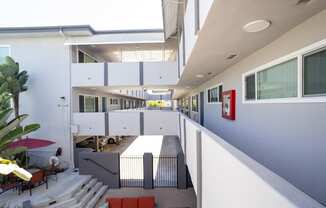 A white building with a red umbrella and a red bench.