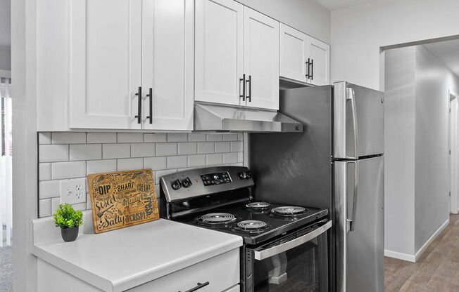 a white kitchen with stainless steel appliances and white cabinets