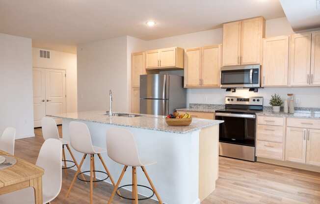 a kitchen with a large island with white chairs and a counter top