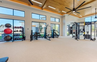 A spacious gym with a variety of equipment and a ceiling fan.