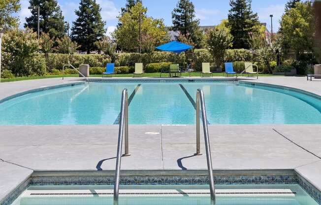 a swimming pool with a blue umbrella and chairs around it