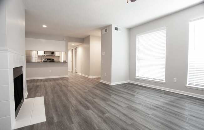 an empty living room with a fireplace and a kitchen