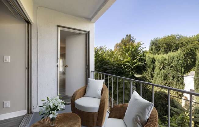 a balcony with two wicker chairs and a table