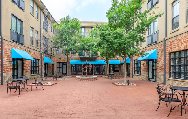 A courtyard with tables and chairs surrounded by brick buildings.