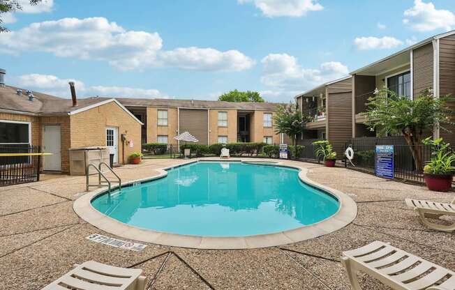 A small pool surrounded by a concrete patio and lounge chairs.