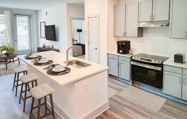 A kitchen with white cabinets and a white island with a sink.