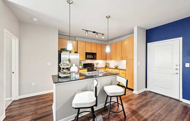 Open-concept kitchen with granite countertops and stainless steel appliances at The Grand at Upper Kirby apartments in Houston, TX