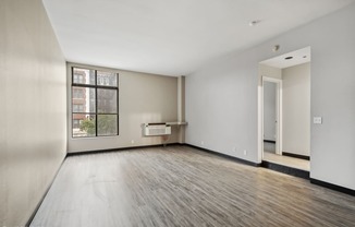 an empty living room with wood floors and a large window