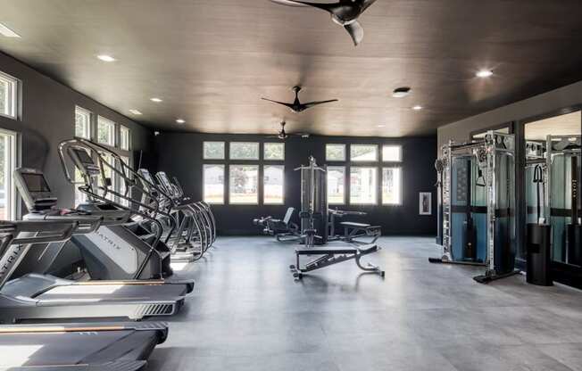 a home gym with plenty of exercise equipment and windows