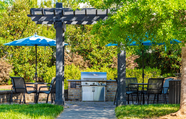 a patio with a grill and tables with umbrellas