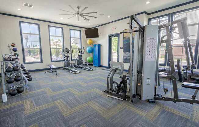 A gym with a variety of equipment including a weight rack, treadmill, and exercise balls.