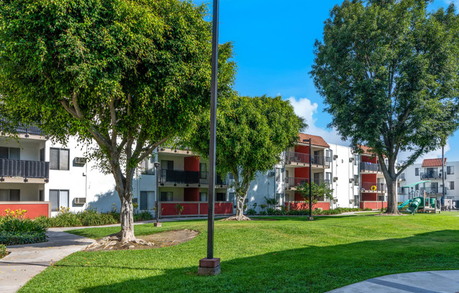 a park with trees in front of an apartment building