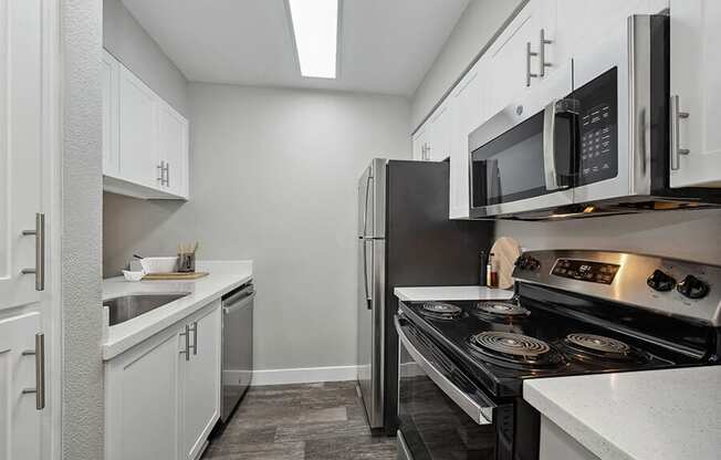 Model Kitchen with White Cabinets and Wood-Style Flooring at Crystal Creek Apartments located in Phoenix, AZ.