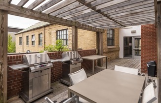 a patio with a barbecue grill and a table with chairs