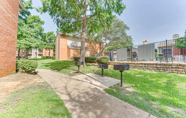 A tree stands in a grassy area in front of a brick building at Copper Hill Apartments, Bedford, TX, 76021