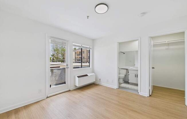 A white room with a window and a door leading to a bathroom.