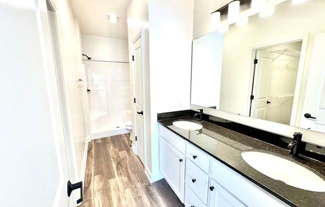 A bathroom with a sink, mirror, and wooden floor.