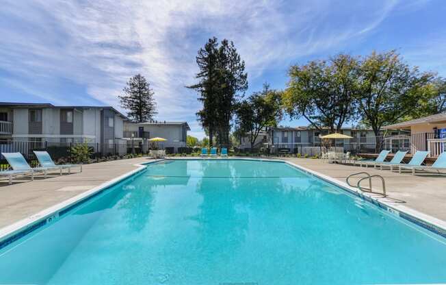 Community swimming pool with bright blue skies and mature trees in the distance. at Renaissance Park Apartments, Davis