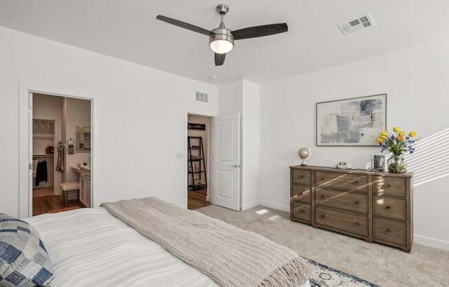 A bedroom with a bed, dresser, and a ceiling fan.