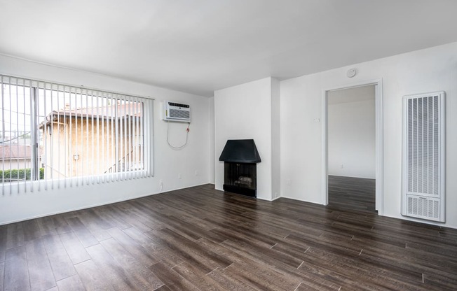 an empty living room with wood floors and a fireplace