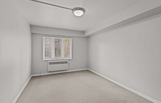 A room with a window and a carpeted floor.