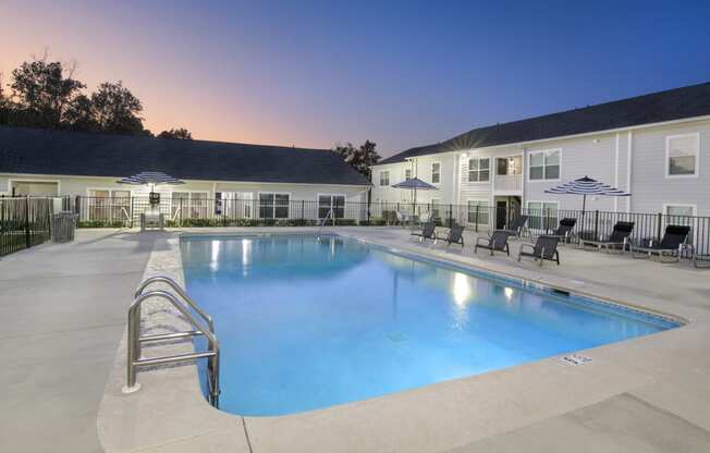 a swimming pool with chairs and umbrellas in front of a building