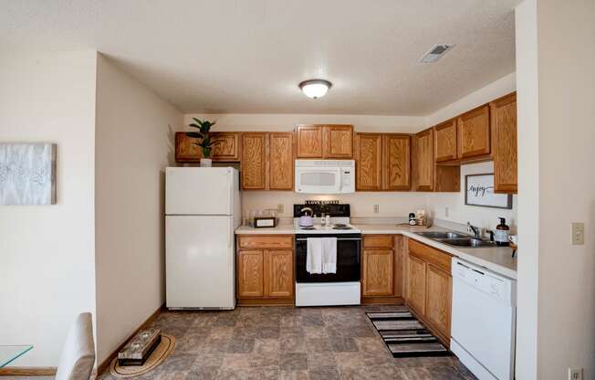 Spacious Kitchen With Tile-Style Flooring, Oak Cabinets & White Appliances