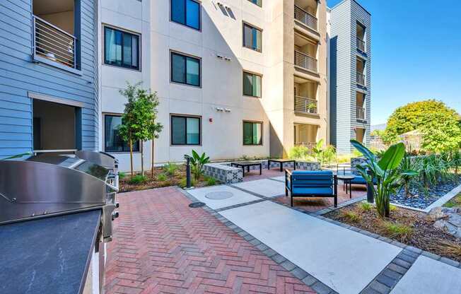 A modern apartment complex with a brick patio and outdoor furniture.