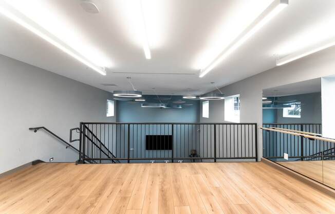 A spacious room with wooden floors and a staircase with metal railings.