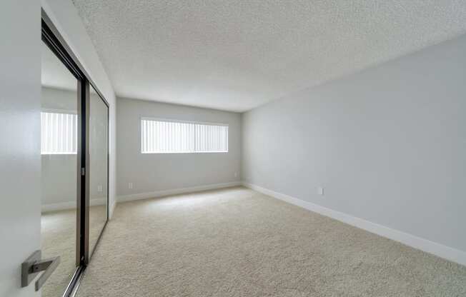 the spacious living room of an apartment with white walls and carpet