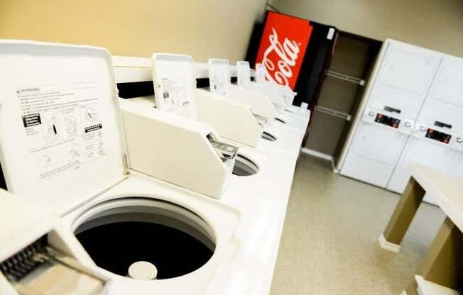 A row of Coca-Cola vending machines are lined up in a room.