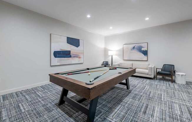 A room with a pool table and two chairs.