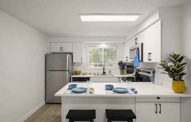 a kitchen with white cabinets and a white island with two black stools in front of it