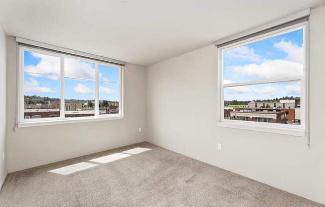 A room with two windows overlooking a cityscape.
