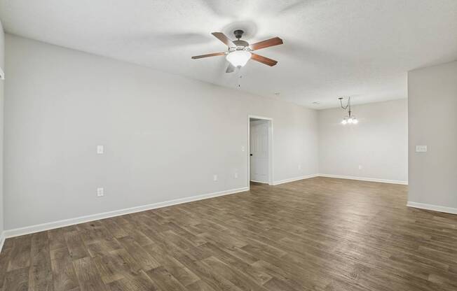 A room with a ceiling fan and wooden flooring.