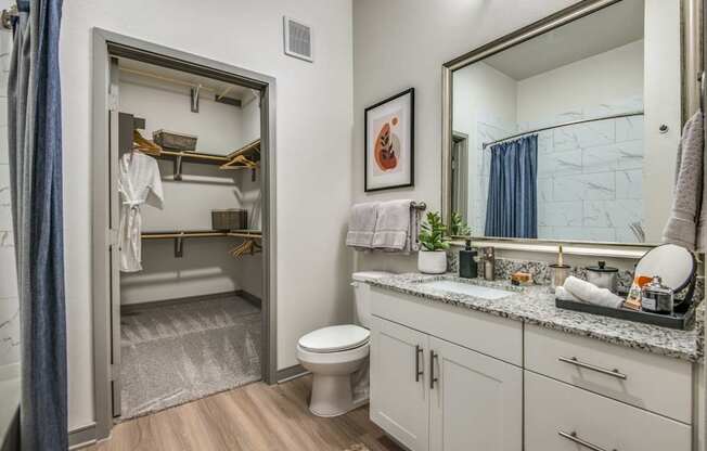 A bathroom with a toilet, sink, and mirror.