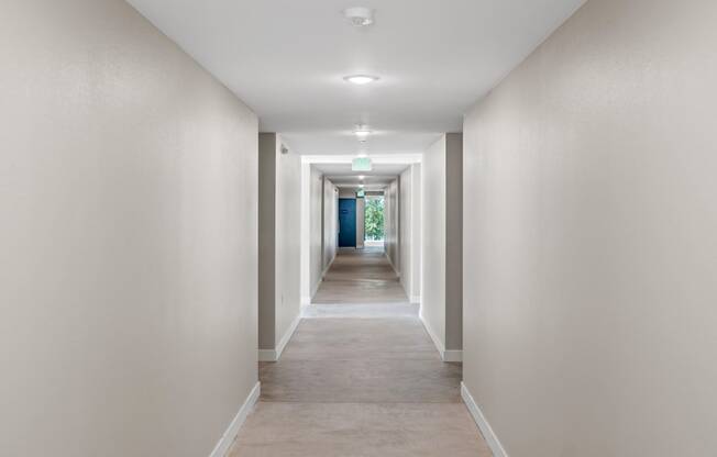 a long corridor with white walls and beige carpet at Loma Villas Apartments, San Bernardino California