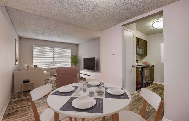 a dining area with a table and chairs and a kitchen in the background