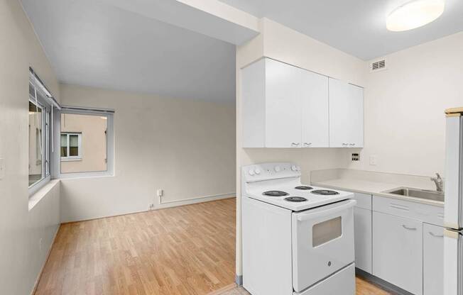 an empty kitchen with white appliances and white cabinets