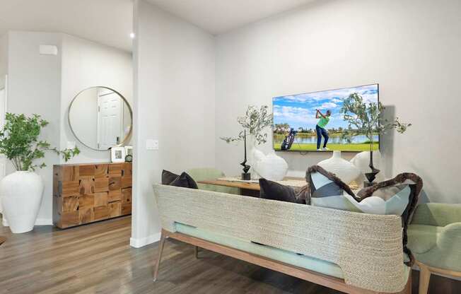 A bedroom with a bed, a mirror, a painting, and a plant.