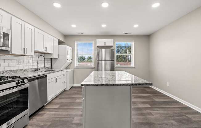 a kitchen with white cabinets and a large island with granite countertops