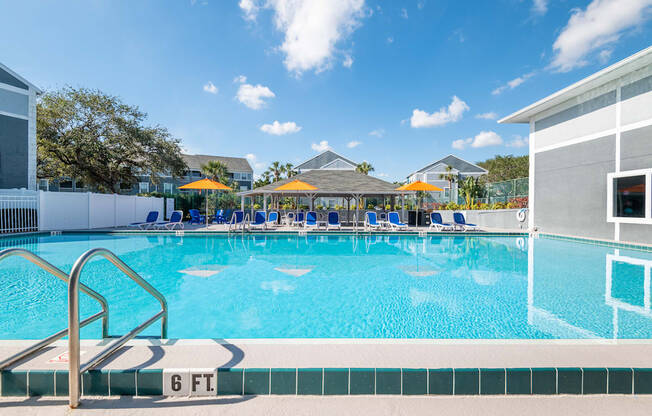 a large swimming pool with blue and yellow umbrellas in the background