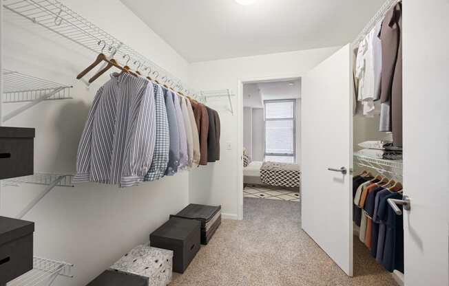 a walk in closet with clothes hanging on a rack and a door to a bedroom