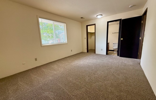 A room with a carpeted floor and a window.