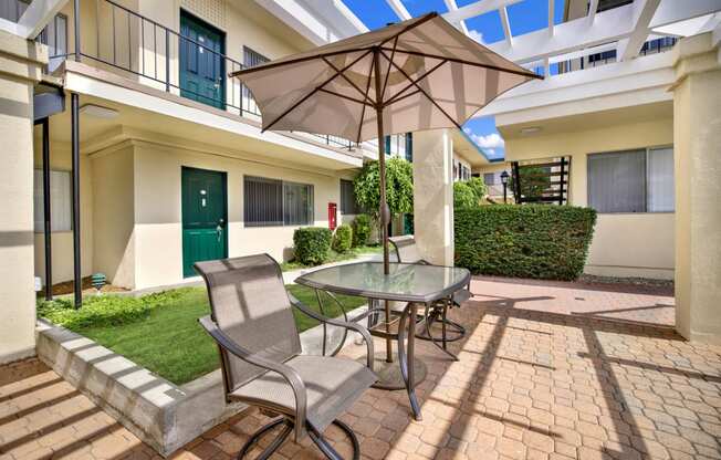 a patio with an umbrella and a table with chairs at Olive Tree Apartments, Torrance, CA 90503